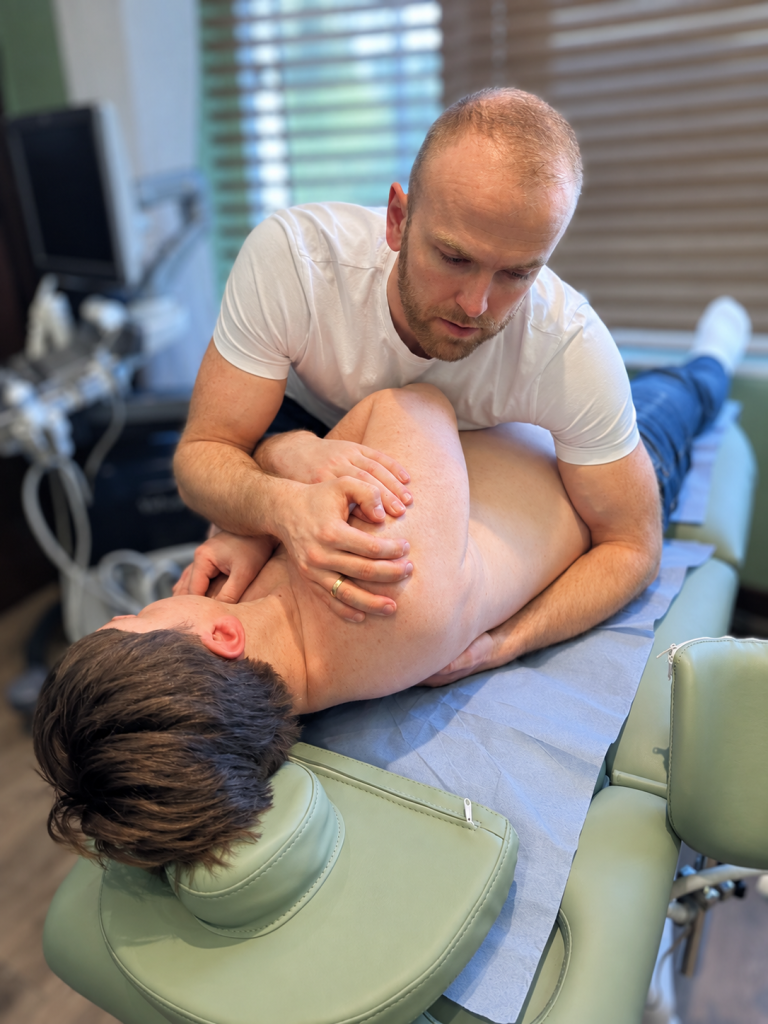 Physiotherapist Piotr Borysiak providing hands-on shoulder treatment to a patient at Phoenix Medical Clinic in Watford